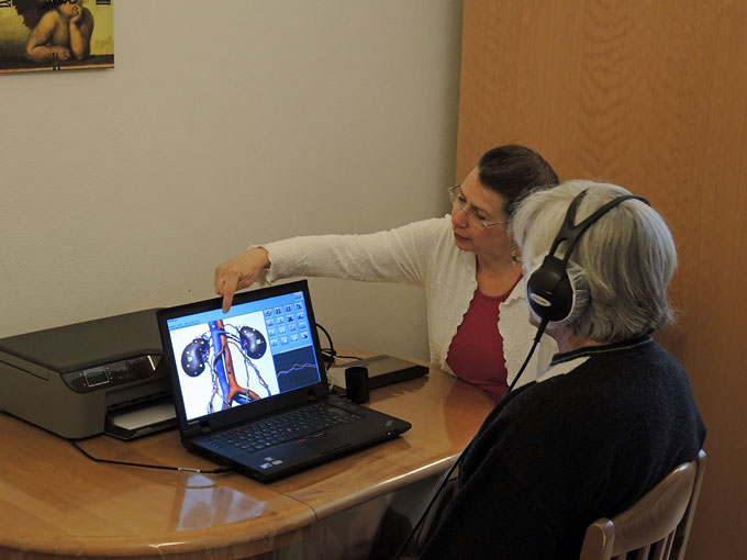 Foto einer Bioresoanz-Anwendung mit einer
                        Patientin mit Kopfhrer und Therapeutin Sylvia
                        Kahlert